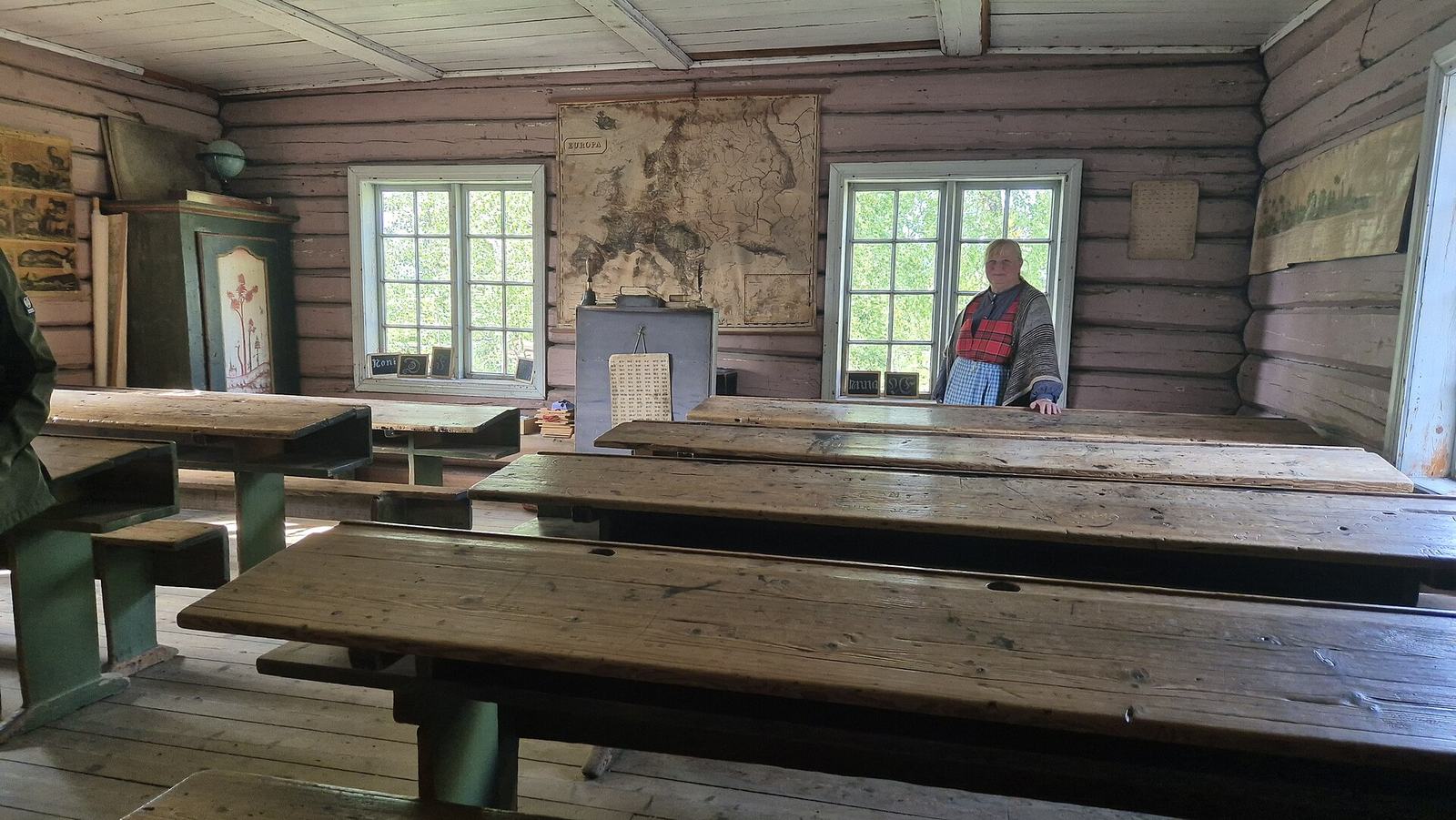 Traditional log-built classroom with rows of long wooden desks